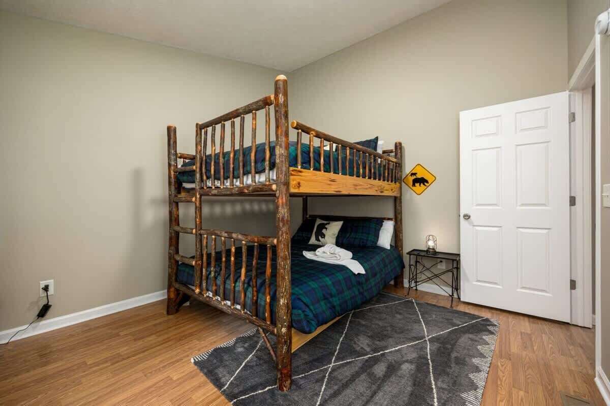 A bunk bed room with a wooden ladder, a small bedside table, a nightstand, and a door.