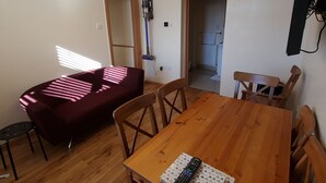 Spiseområde med et træbord, stole og en fjernbetjening på bordet.