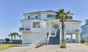 A two-story house with a front porch, a garage, and a staircase leading to the entrance.