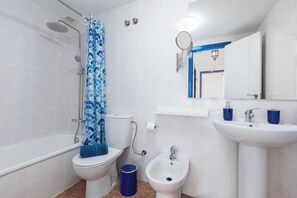 A bathroom with a bathtub, toilet, bidet, and sink.