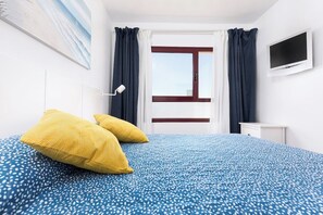 Une chambre d’hôtel avec un lit, une télévision, une fenêtre et des rideaux.