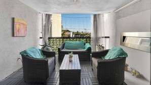 Un balcone con mobili in vimini, un tavolino con una pianta e vista sulla città.