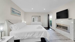 Una camera da letto moderna con un letto, un comodino, una TV e un camino.