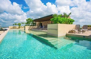 Une piscine aux eaux cristallines, dotée de chaises longues et d’un espace salon abrité.