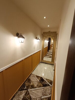 Stunning hallway with polished floor, elegant wallpaper, and ornate mirror.