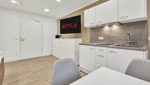 Ett modernt kök med vita skåp, en inbyggd ugn och en stor platt-TV som visar "NETFLIX".
