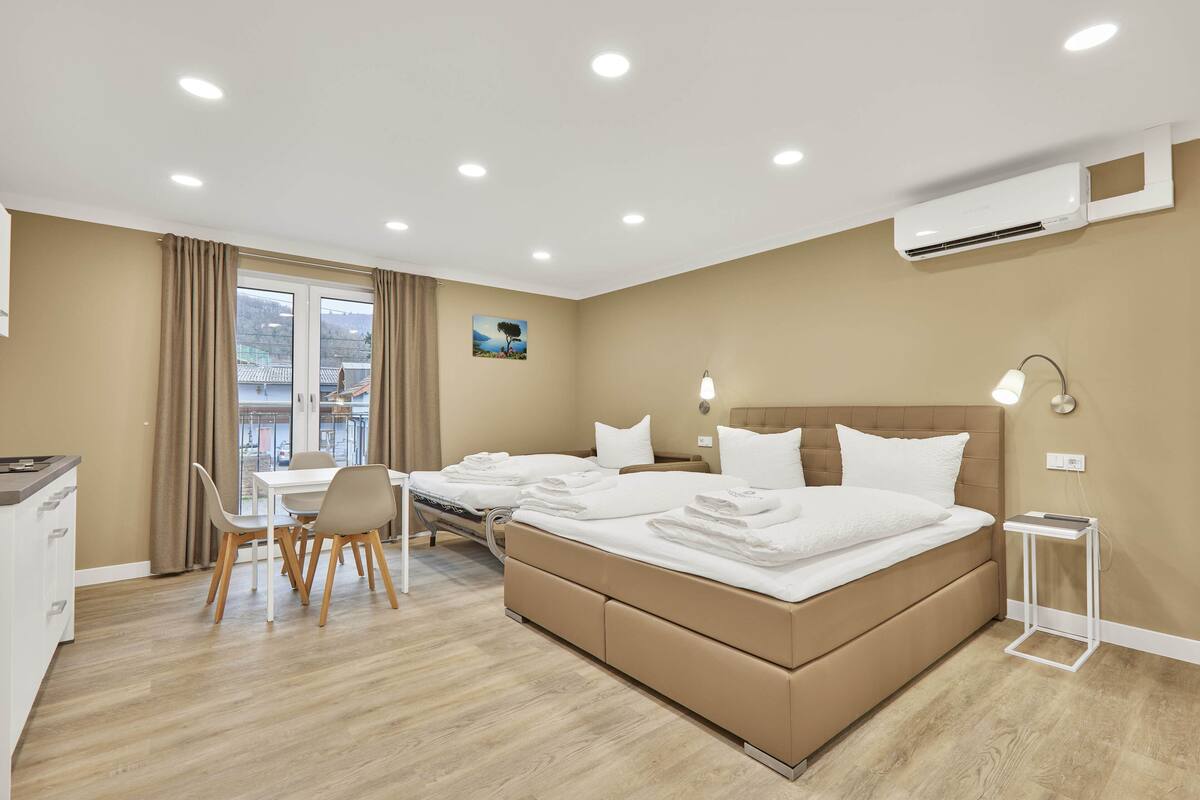 Et hotelværelse med seng, sengebord, lampe og udsigt ud.