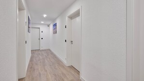 En hall med vita väggar, trägolv och dörrar numrerade 5 och 6.