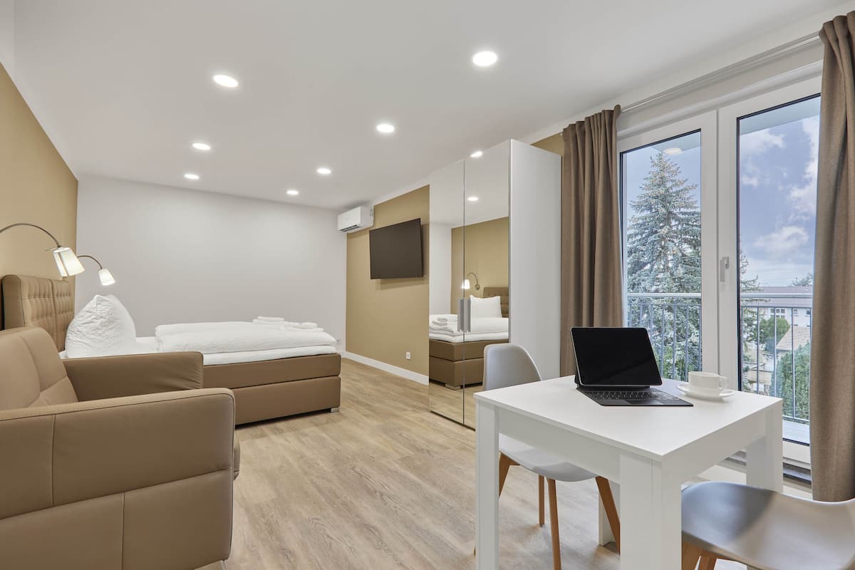 Et moderne hotelværelse med en seng, et skrivebord med en bærbar computer, en stol og en sofa.