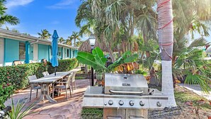 An outdoor patio with a grill, a table with chairs, and a blue umbrella. - The Charter House (Hollywood)