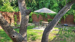 Een achtertuin met houten omheining, een tafel met stoelen en een parasol.