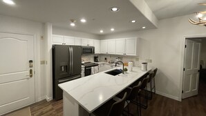 A modern kitchen with white cabinetry, a large island with bar stools, a built-in oven, and a microwave. - Gorgeous Ski-In Ski-Out Condo on Beaver Creek Mountain (Beaver Creek)