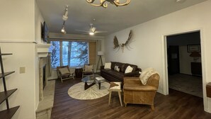 A living room with a fireplace, a round coffee table, a sofa, and a chandelier. - Gorgeous Ski-In Ski-Out Condo on Beaver Creek Mountain (Beaver Creek)