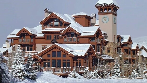 A large, multi-story lodge with a prominent clock tower, surrounded by snow-covered trees. - Gorgeous Ski-In Ski-Out Condo on Beaver Creek Mountain (Beaver Creek)