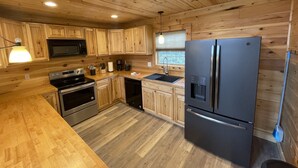 A modern kitchen with wooden cabinetry, stainless steel appliances, and a black refrigerator. - Rustic Elegance, 1 bedroom cabin in the heart of Jonesborough. (Jonesborough)