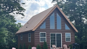 A log cabin with a large front porch, multiple windows, and a fire pit. - Rustic Elegance, 1 bedroom cabin in the heart of Jonesborough. (Jonesborough)