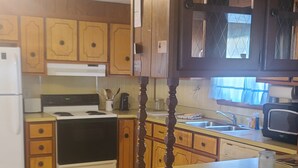 A kitchen with wooden cabinets, a white stove, a sink, and a microwave.