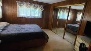 A bedroom with a bed, a dresser, a mirror, and a ceiling fan.