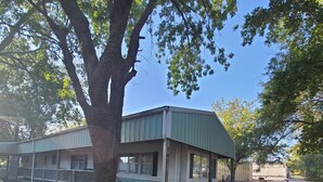 A two-story building with a covered porch and a large tree in front.