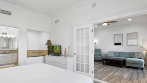 A bedroom with a bed, a TV, a dresser, and a door leading to a living area with a sofa and a coffee table. - Amazing Golf View Condo Best view in Reunion! (Kissimmee)