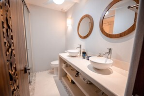 Un baño moderno con dos lavamanos, un inodoro y un espejo con marco de madera.