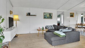 A living room with a grey sofa, a TV on a stand, a lamp, a painting, and a wooden floor. - Cozy home in Karrebæksminde with WiFi (Karrebæksminde)