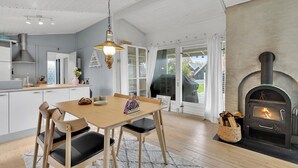 A modern kitchen with a dining area, a fireplace, and a view of the outdoors. - Cozy home in Karrebæksminde with WiFi (Karrebæksminde)