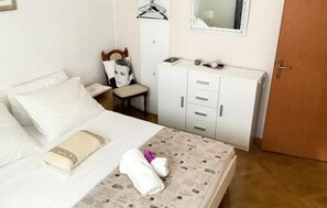 Una habitación de hotel con cama, una silla, un armario y una puerta.