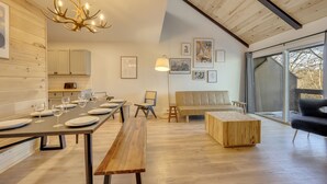 Un espace repas moderne avec une longue table en bois dressée pour le repas, un banc et un canapé.