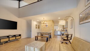 Un vaste espace de vie doté d’un plancher en bois, d’une table basse centrale, d’un canapé et d’une table à manger avec des chaises.