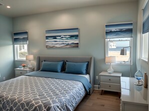 Relax in this serene bedroom with a large bed, nightstand, dresser, and ocean views.