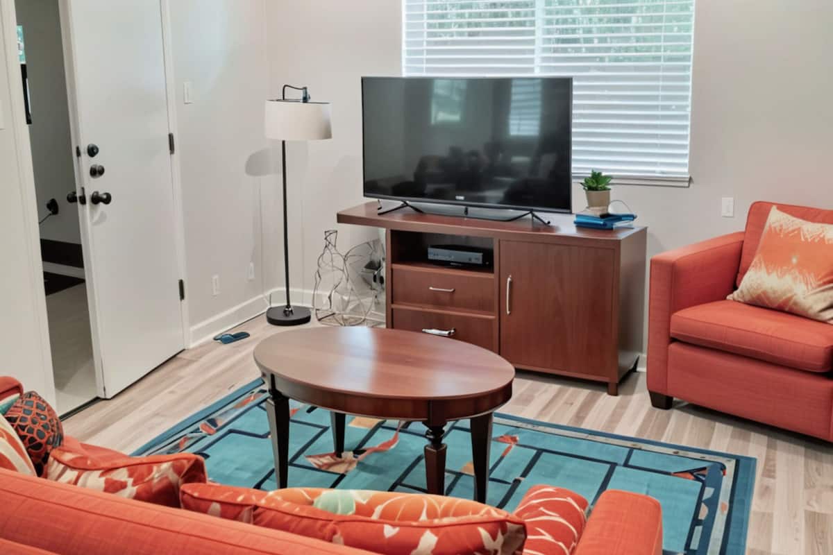 Un salon avec un téléviseur, un canapé et une table basse.