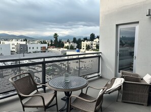 Enjoy breathtaking views of the city from this balcony with a round table and comfortable wicker chairs.