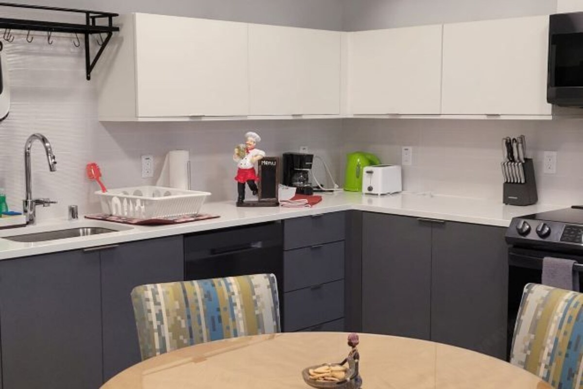 A modern kitchen with white cabinets, a coffee maker, a toaster, and a small statue on the counter.