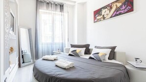 A modern hotel room with a large bed, a bedside table with a cup, a window with curtains, and a painting on the wall. - Nice and elegant apartment in the center (Oliveri)