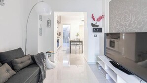 A modern living room with a sofa, a TV, and a dining area in the background. - Nice and elegant apartment in the center (Oliveri)