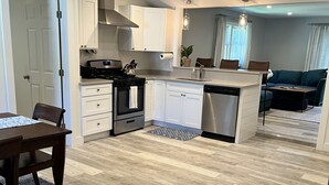 Una cocina moderna con armarios blancos, electrodomésticos de acero inoxidable y una mesa de comedor de madera.