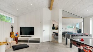 A modern kitchen with a dining area, a TV, and a foosball table.
