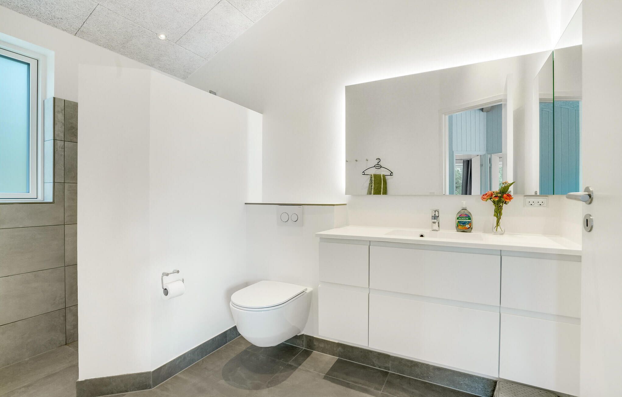 A modern bathroom with a toilet, sink, and mirror.