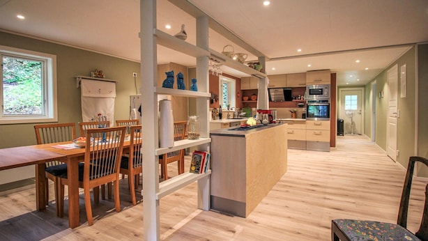 Une cuisine moderne avec un plancher en bois, un coin repas avec une table et des chaises, et un petit îlot central doté d’un évier.