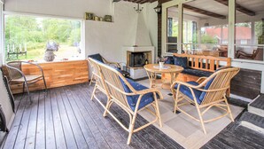 Un espace extérieur accueillant, aménagé avec des meubles en osier et doté d’une cheminée.