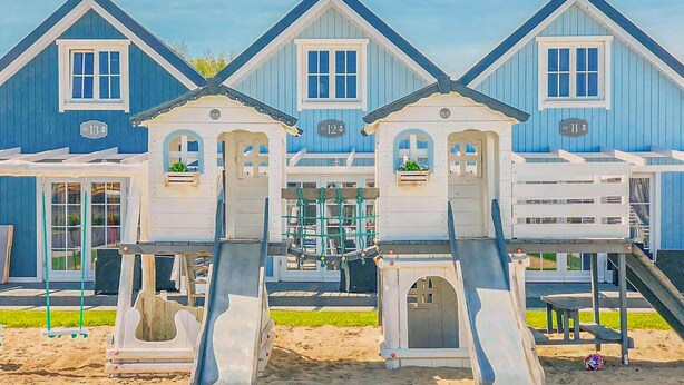 A beachfront building with multiple levels, including a slide and a small boat house.