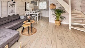 A modern interior with a grey sofa, a small round table, a staircase, and a kitchen area.