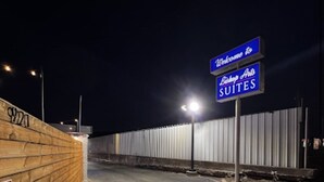 A nighttime view of a hotel entrance with a wooden wall, a 'Welcome to Suites' sign, and a 'No Entry' sign. - Bishop Arts Suites (Dallas)