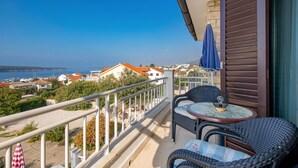 Ein Balkon mit Korbmöbeln, einem Tisch und Blick auf das Meer und die Gebäude.