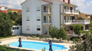 Ein zweistöckiges Gebäude mit Swimmingpool, Steinaußenwand und Balkonen.