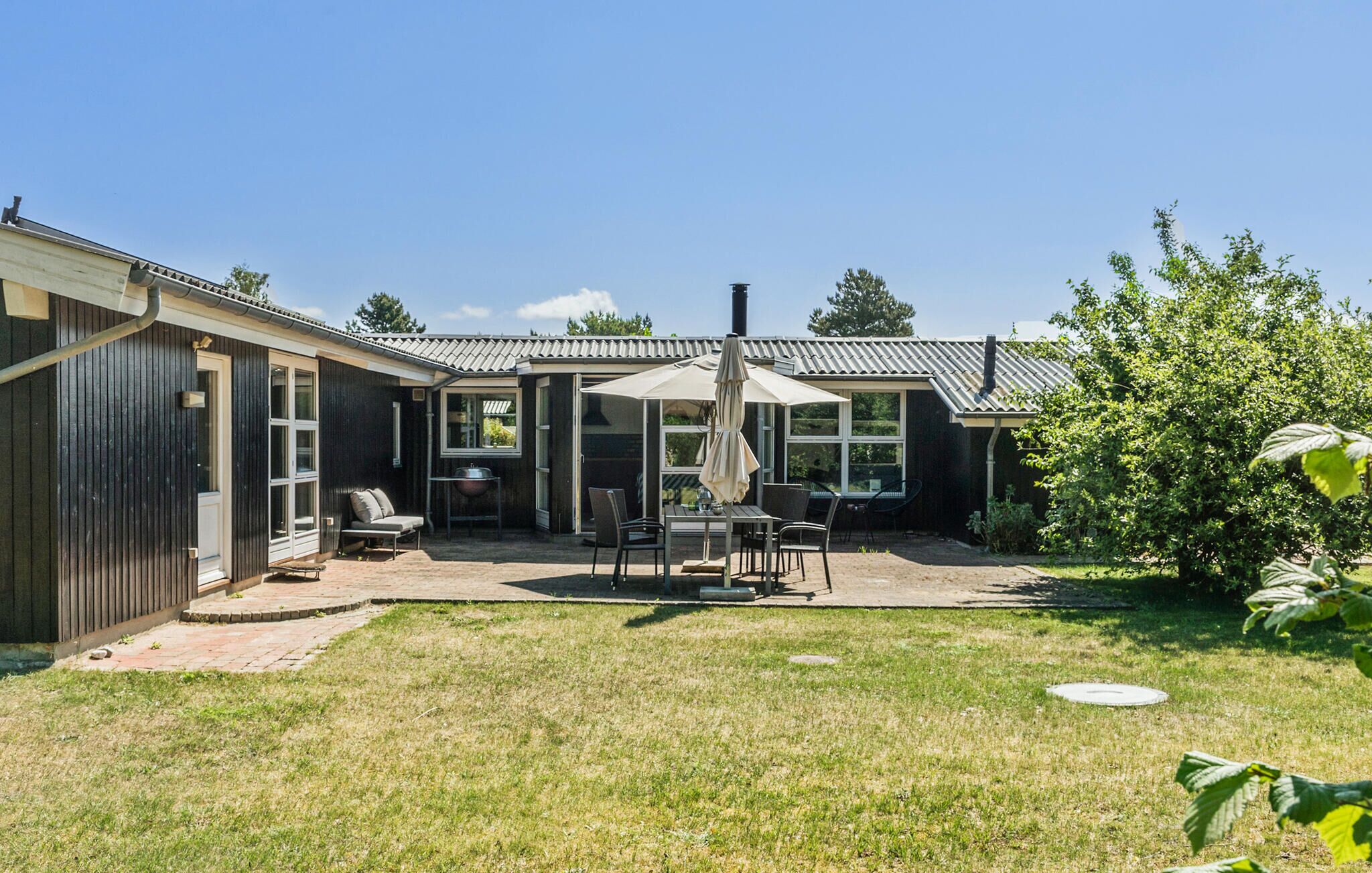 A house with a patio area featuring a table and chairs, a grill, and a covered seating area.
