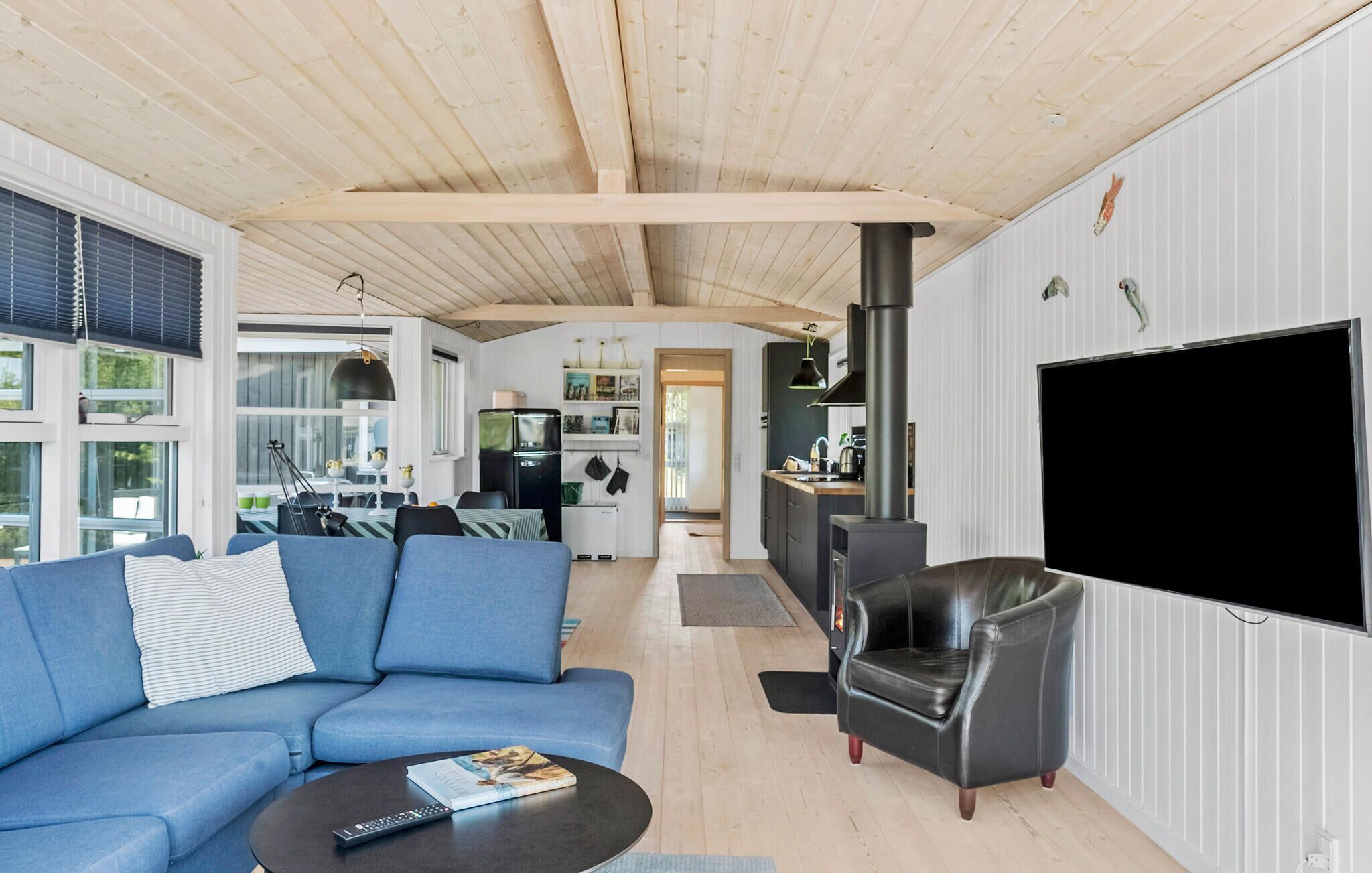 Una sala de estar moderna con un sofá azul, un sillón de cuero negro y un televisor de pantalla plana montado en la pared.