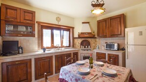 A kitchen with wooden cabinets, a built-in oven, a microwave, and a dining table set for four. - Beautiful home in Reggio Calabria (Reggio Calabria)