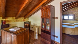 A cozy attic bedroom with wooden beams, a wooden cabinet with glass doors, a bed, and a small desk with books. - Beautiful home in Reggio Calabria (Reggio Calabria)